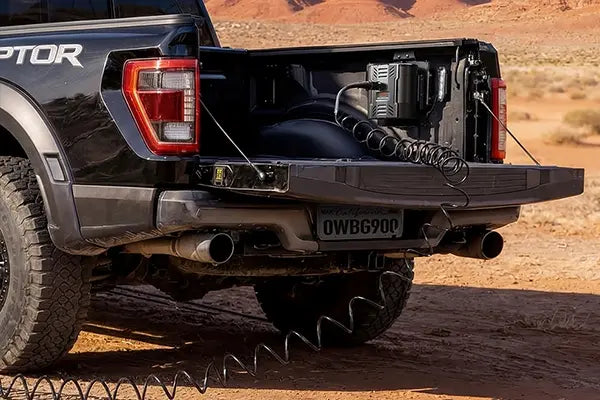 Portable air compressor mounted in a pickup truck bed with coiled hose extending from the vehicle in an outdoor setting